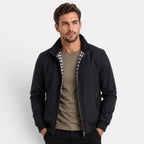 Man wearing a black jacket over a green shirt on a white background