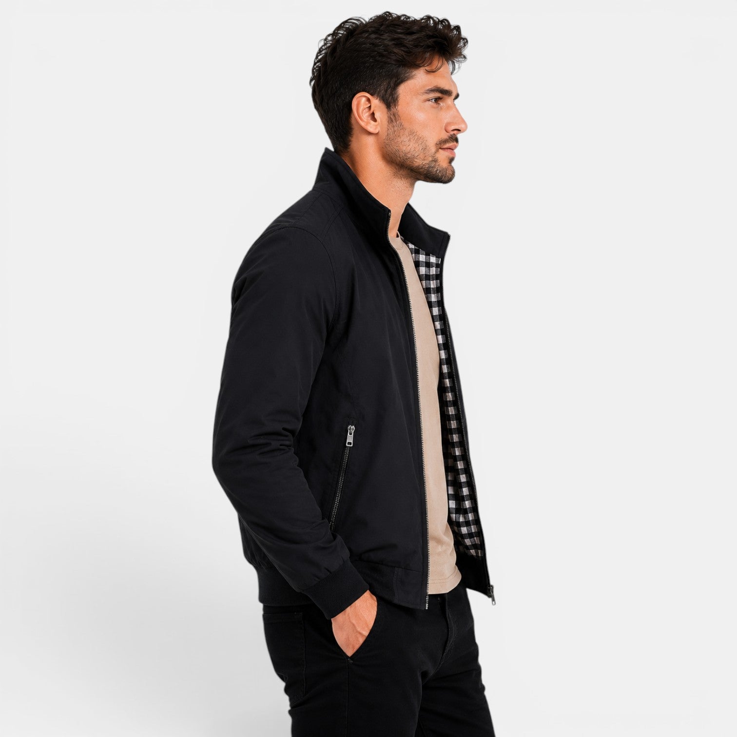 Man wearing a black jacket over a checkered shirt on a white background