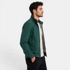 Man wearing a green jacket over a checkered shirt on a white background