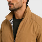 Man wearing a brown jacket with a checkered shirt underneath on a white background