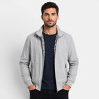 Man wearing a gray jacket over a dark shirt on a light gray background