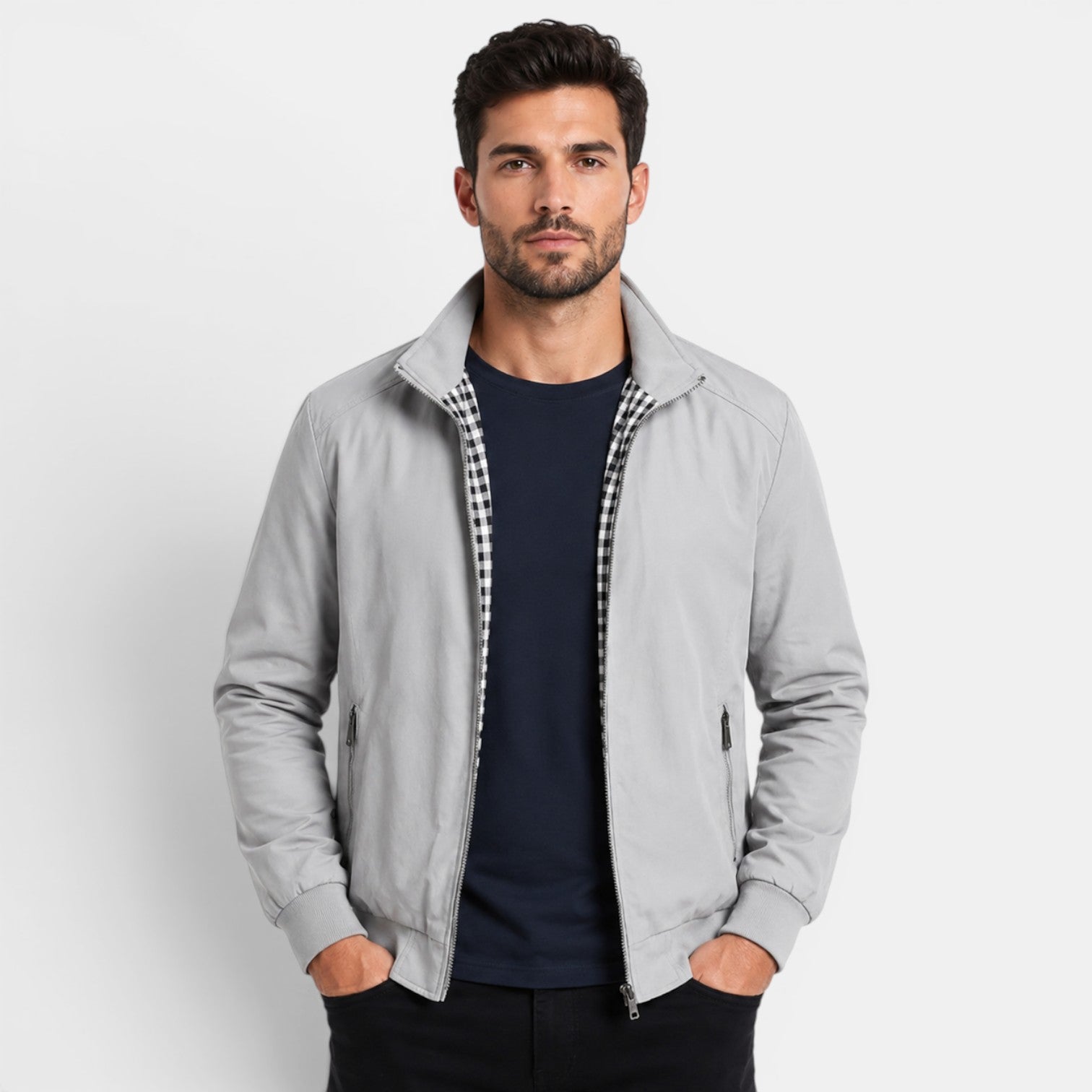 Man wearing a gray jacket over a dark shirt on a light gray background