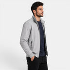 Man wearing a gray jacket over a checkered shirt on a white background