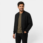 Man wearing a black bomber jacket over a green shirt on a white background