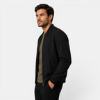 Man wearing a black jacket over a green shirt on a white background