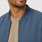 Man wearing a blue jacket over a beige shirt on a plain background