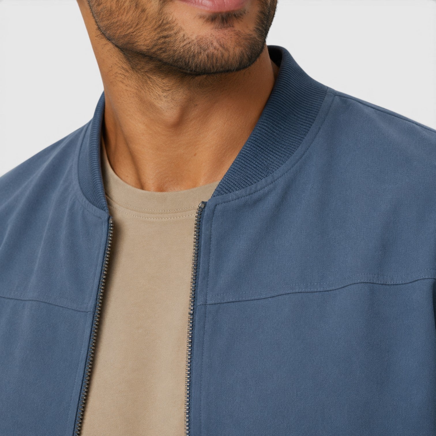 Man wearing a blue jacket over a beige shirt on a plain background