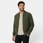 Man wearing a green bomber jacket over a beige shirt on a white background