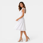 Woman wearing a white dress with ruffled shoulders on a white background