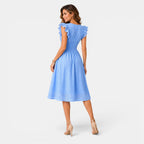 Woman wearing a light blue dress with ruffled sleeves on a white background