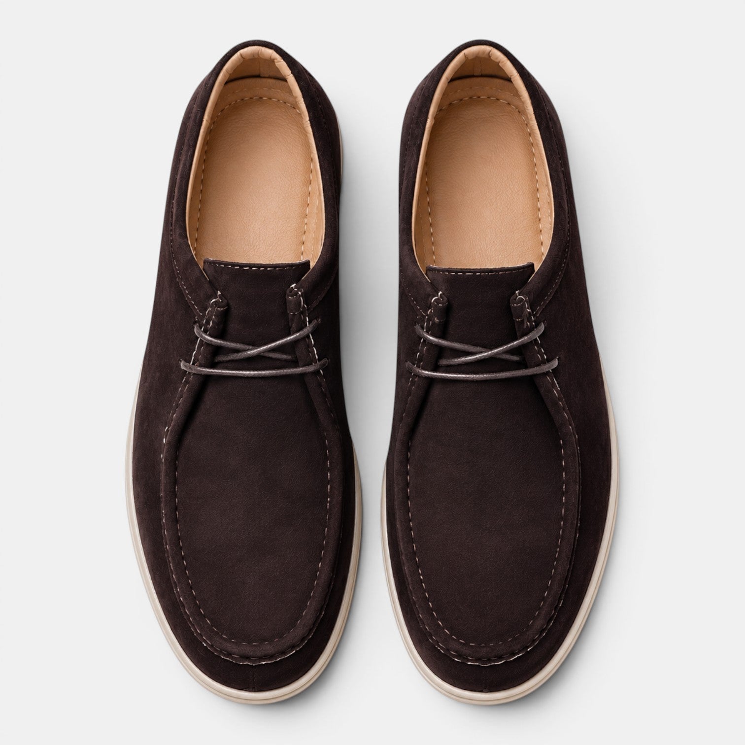 Top view of a pair of dark brown suede lace-up shoes with white soles against a light gray background.