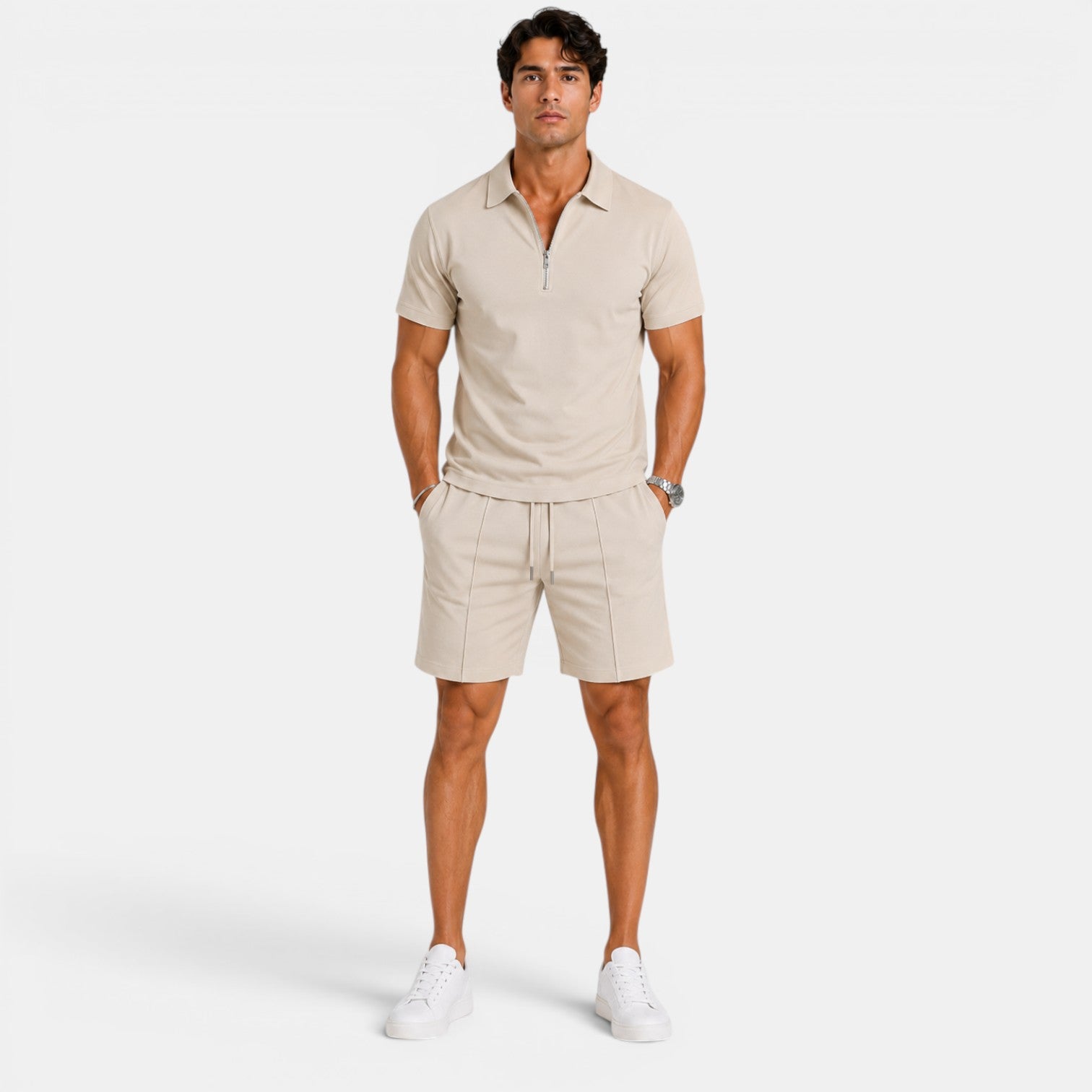 Man wearing a beige zip-collar polo shirt with matching drawstring shorts and white sneakers, standing against a light gray background.