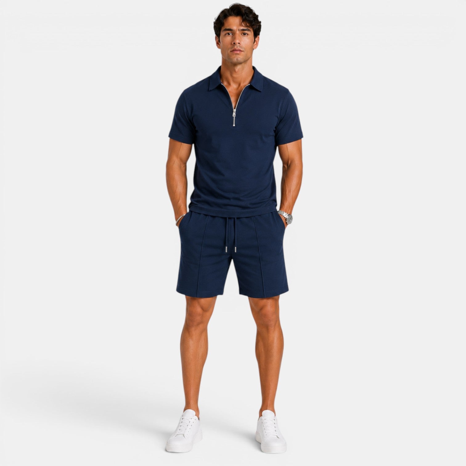 Man wearing a navy blue zip-collar polo shirt with matching drawstring shorts and white sneakers, standing against a light gray background.