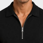Close-up of a black zip-collar polo shirt, highlighting the silver zipper and collar detail.