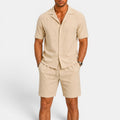 Man wearing a beige short-sleeve shirt and shorts set on a white background