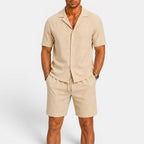 Man wearing a beige short-sleeve shirt and shorts set on a white background
