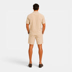 Man wearing a beige polo shirt and shorts set on a white background
