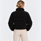 Back view of a woman wearing a black quilted puffer jacket with high collar