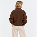 Back view of a woman wearing a brown knit pullover sweater with ribbed cuffs