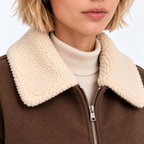 Close-up of women's brown jacket with cream shearling collar and front zipper