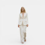 Woman wearing a white suit on a plain background