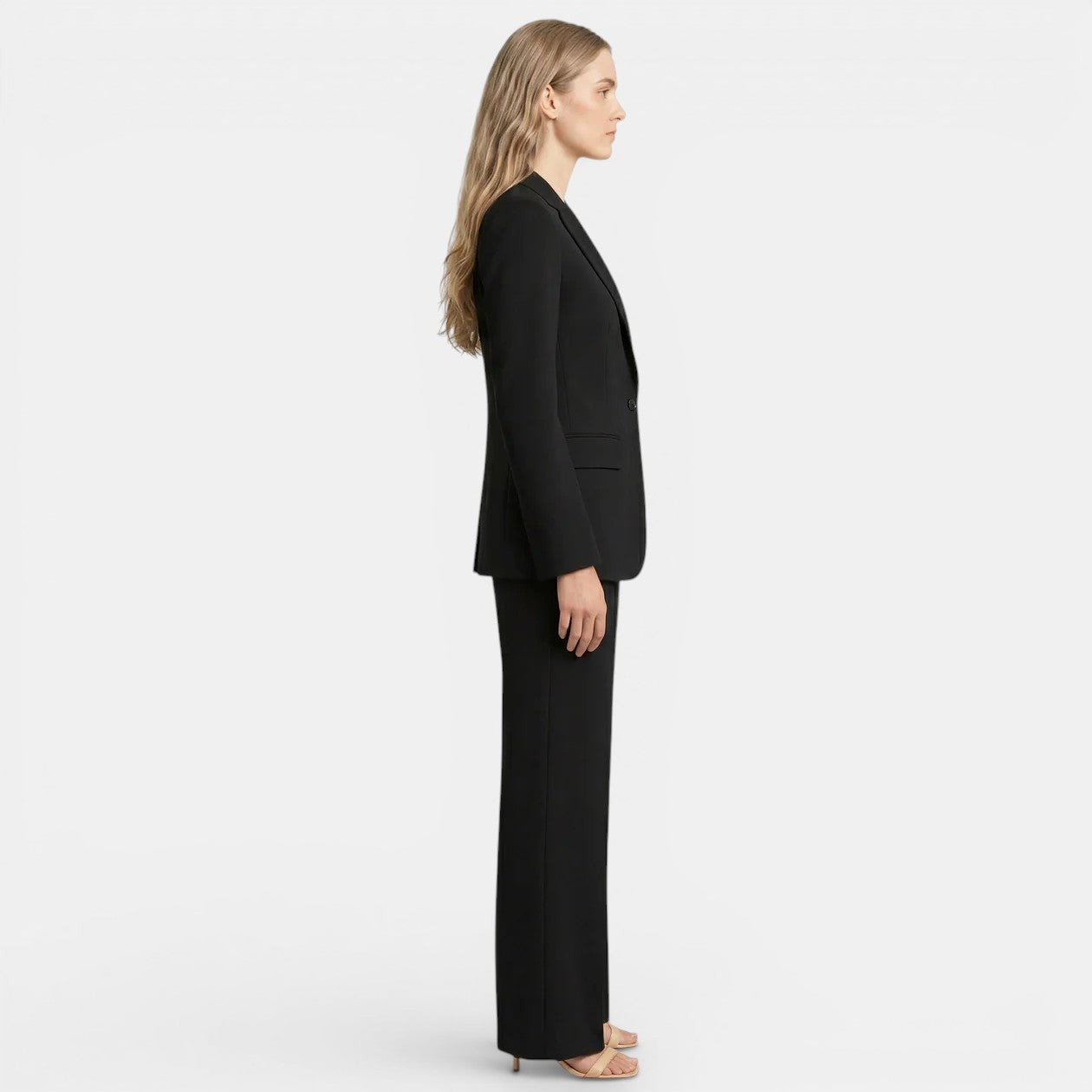 Woman wearing a black suit standing against a white background