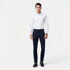 Man wearing a white dress shirt and navy pants on a white background