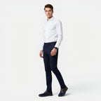 Man wearing a white dress shirt and navy pants on a white background