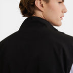 Person wearing a black coat on a plain background