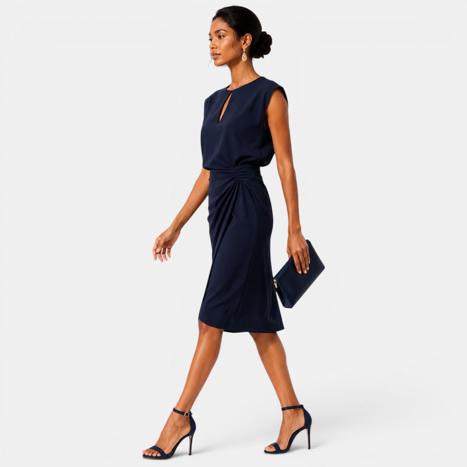 Woman wearing a navy blue dress holding a matching clutch on a white background