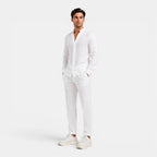 Man wearing a white linen shirt and pants on a white background