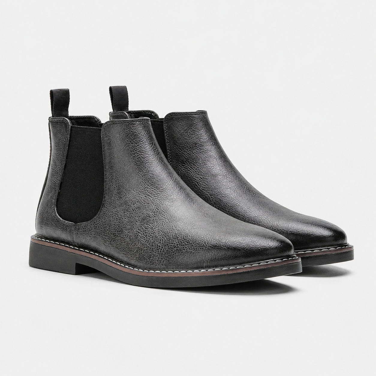 A pair of black leather Chelsea boots with elastic side panels and pull tabs, shown on a light gray background.