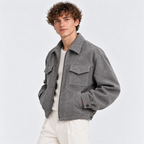 Side view of a man wearing a gray zip-up jacket with flap chest pockets and white trousers