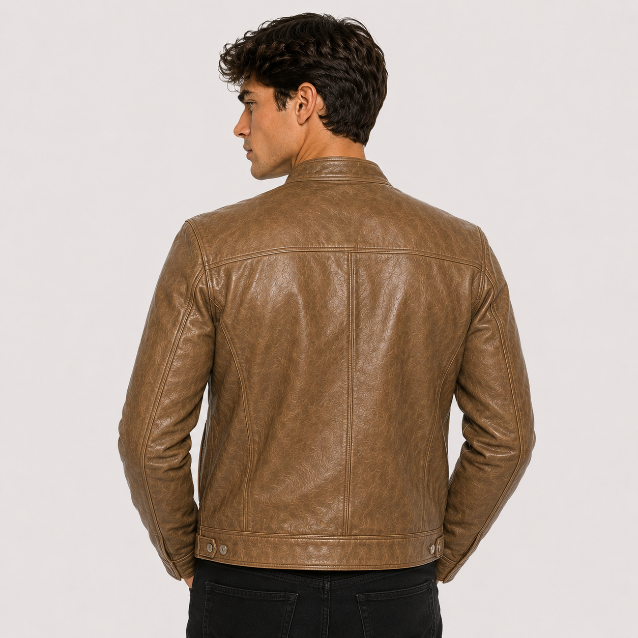 A man wearing a brown leather jacket, shown from the back against a light gray studio background.