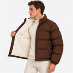 Side view of a man wearing a brown quilted puffer jacket with a stand collar