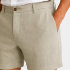 Beige shorts worn by a person on a white background