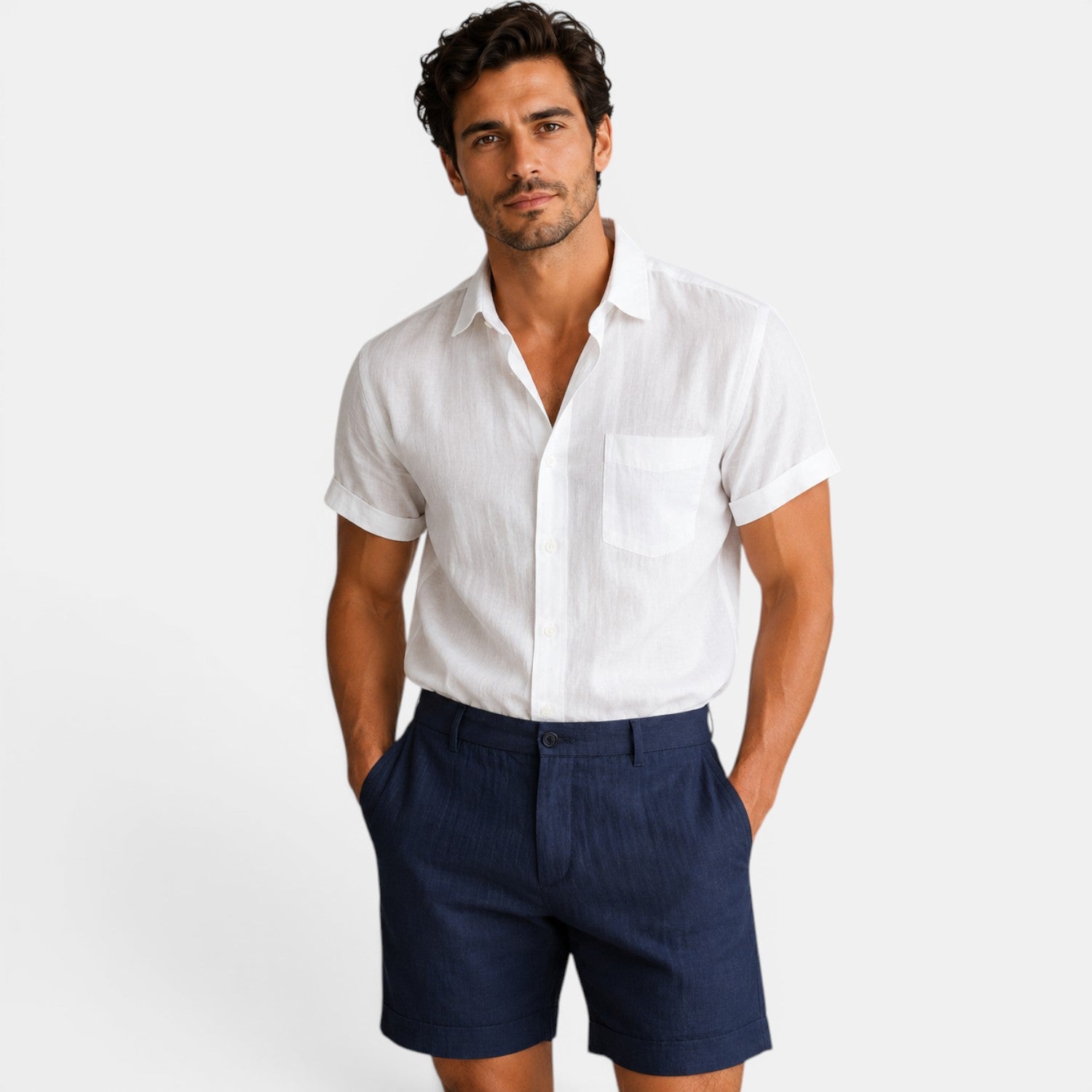 Man wearing a white short-sleeve shirt and navy shorts on a plain background
