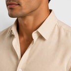 Close-up of a man wearing a beige shirt against a light gray background