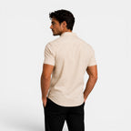 Man wearing a beige short-sleeve shirt on a white background