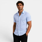 Man wearing a light blue short-sleeve shirt against a white background
