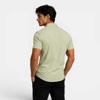 Man wearing a light green polo shirt on a white background