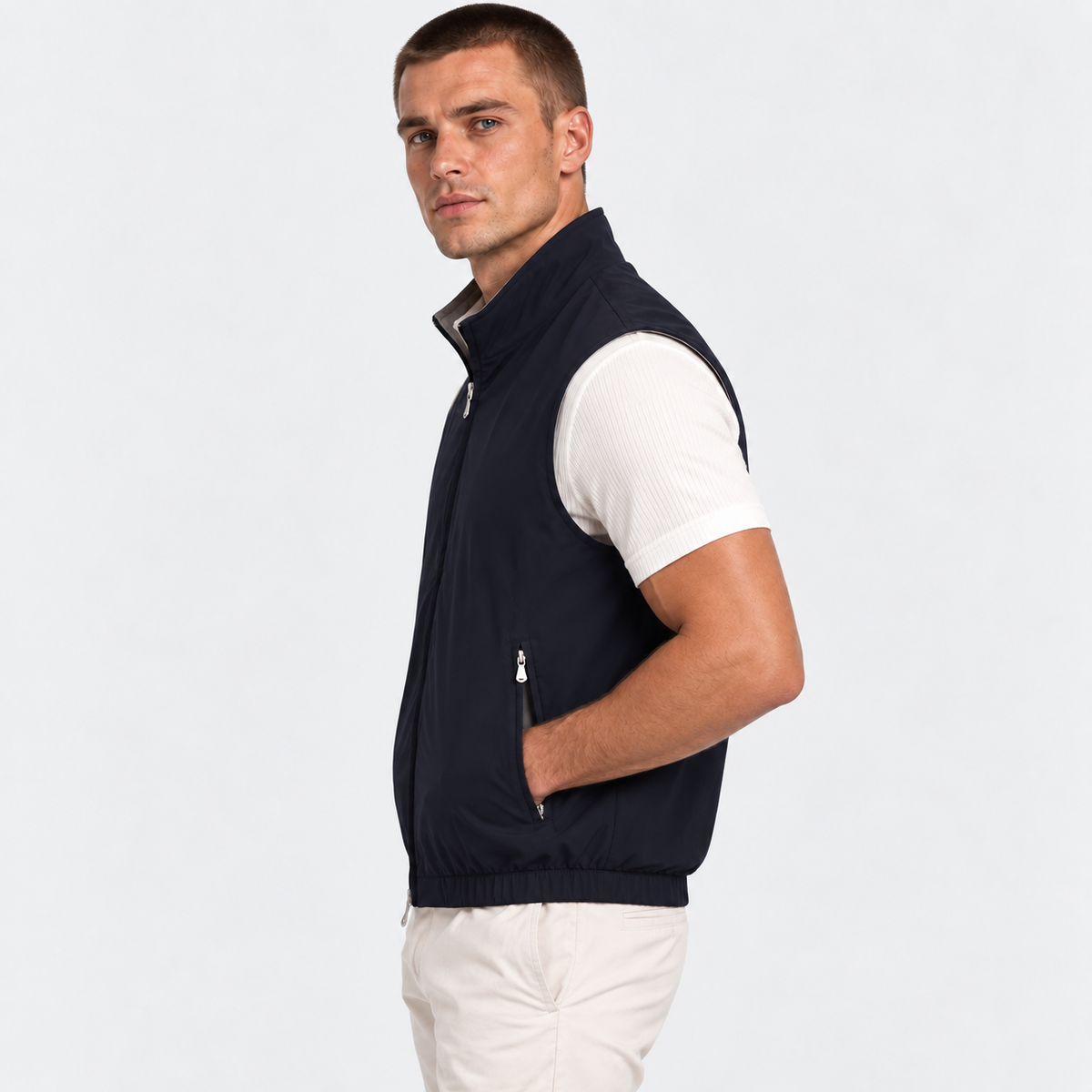 Side view of a man wearing a navy blue zip-up vest over a white shirt