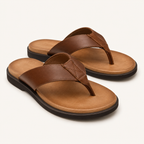 A pair of men's thong sandals in brown, featuring a wide brown leather strap with decorative stitching, a tan cushioned footbed, and a black outsole, shown on a light cream background.