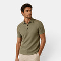Man wearing a green patterned polo shirt on a white background