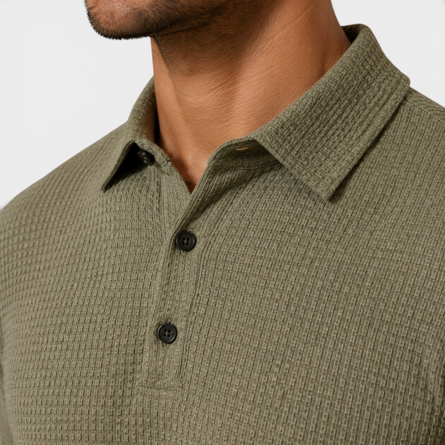 Close-up of a person wearing a green textured polo shirt with black buttons on a light gray background
