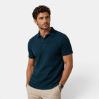 Man wearing a dark blue polo shirt on a light gray background