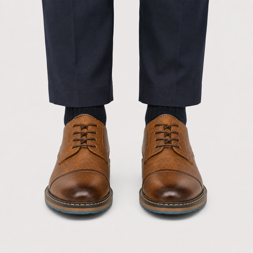 A pair of men's brown leather lace-up dress shoes with a cap toe, shown on a model wearing navy trousers and dark socks against a light gray background.