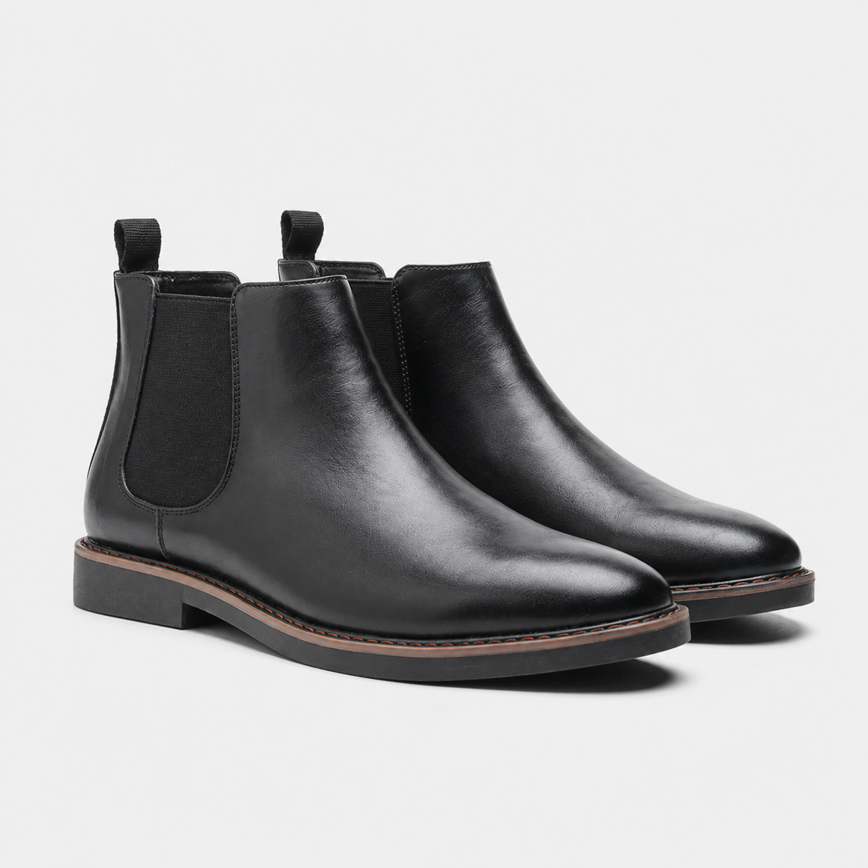 A pair of black leather Chelsea boots with elastic side panels and pull tabs, shown from a three-quarters angle on a light gray background.
