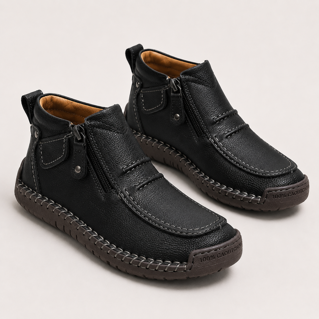 A pair of black leather ankle boots with side zippers, moc-toe stitching, and a braided welt, shown on a light gray background.