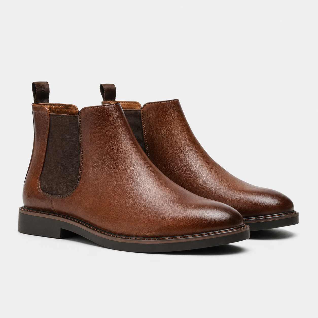 A pair of men's brown leather Chelsea boots with dark brown elastic side panels and pull tabs, shown on a light gray background.